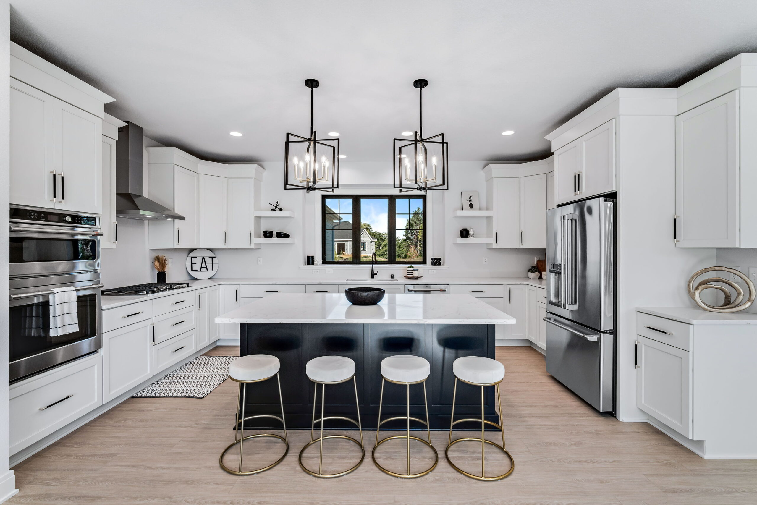 Modern kitchen with large island, bar seating, white cabinets, and stainless steel appliances