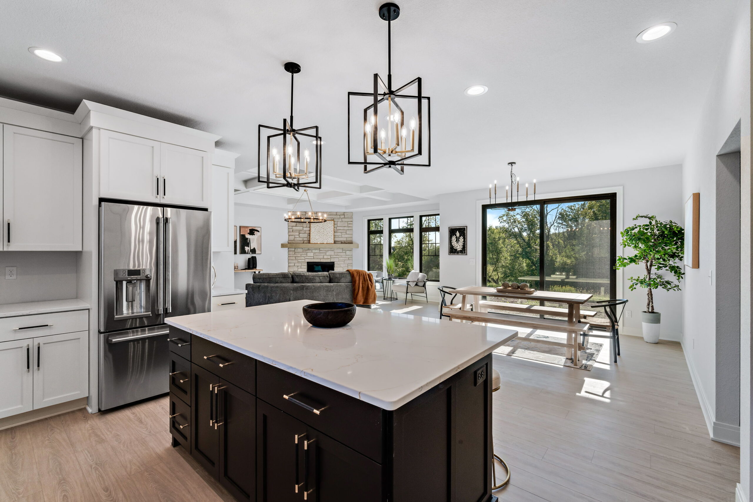 Kitchen with large island and pendant lighting overlooking dining area and living room with fireplace