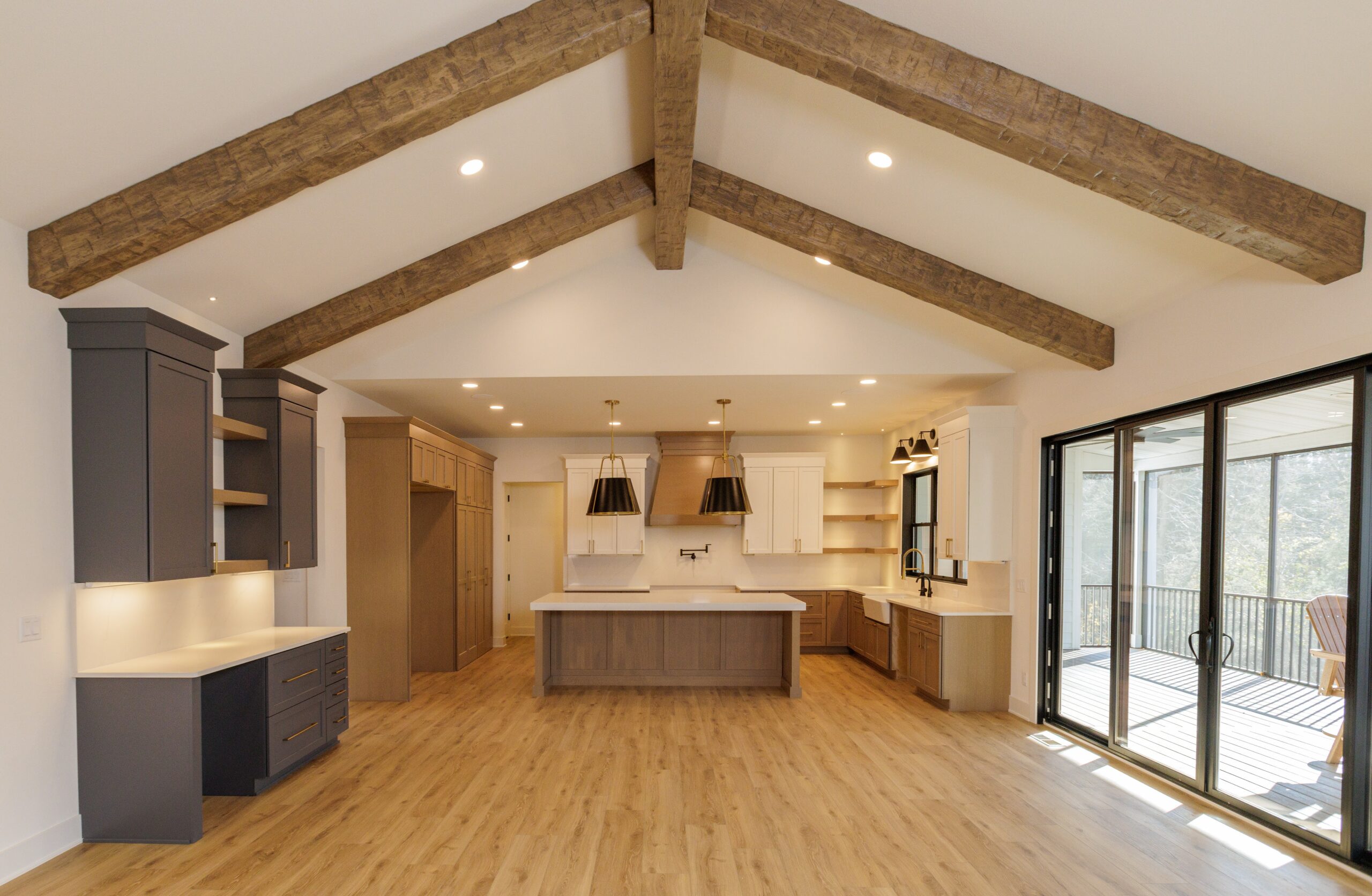 Open concept kitchen with vaulted ceiling, exposed wood beams, large island, and sliding glass doors