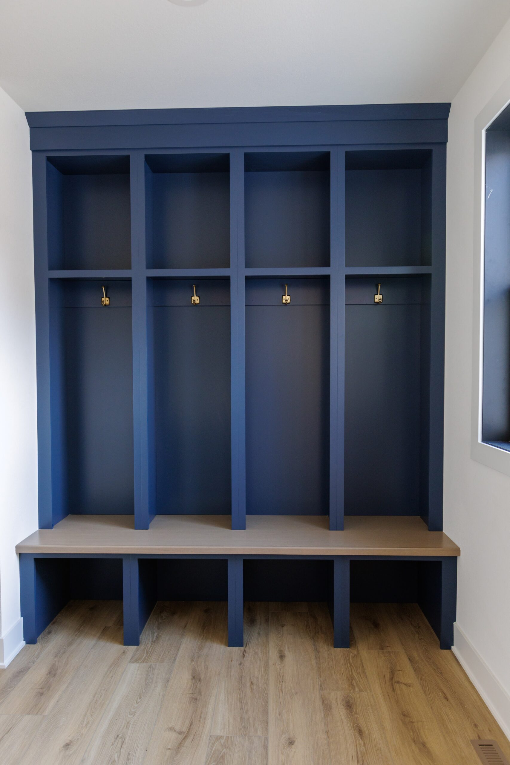 Custom mudroom built-in with blue cabinetry, bench seating, and coat hooks
