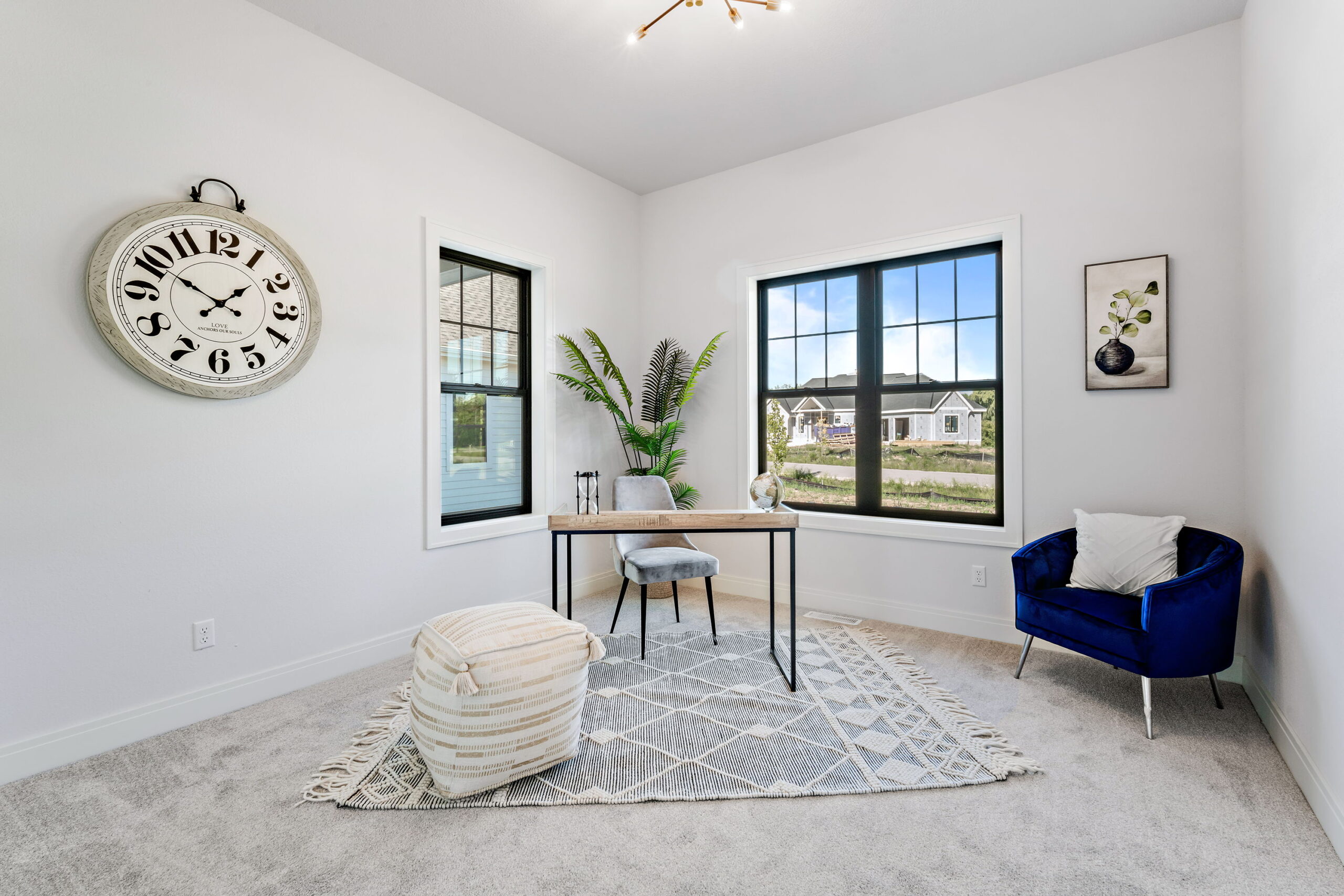 Home office with desk, accent chair, large windows, and natural light