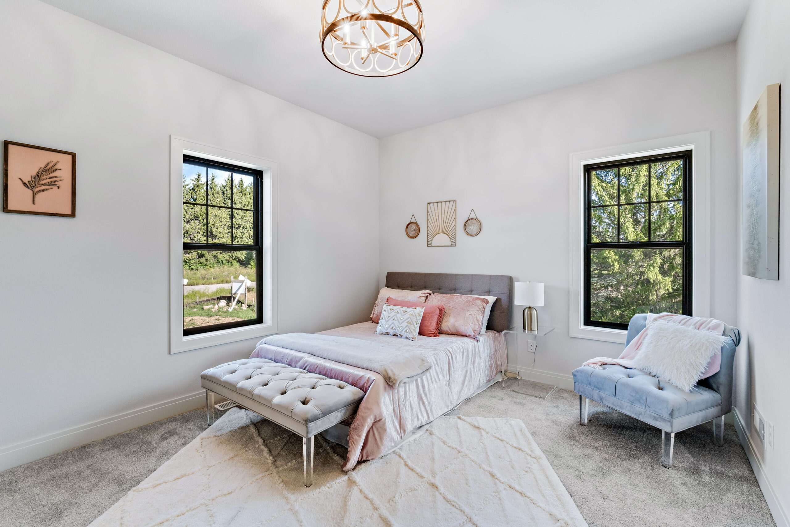 Bedroom with upholstered bed, accent chair, bench seating, and large windows