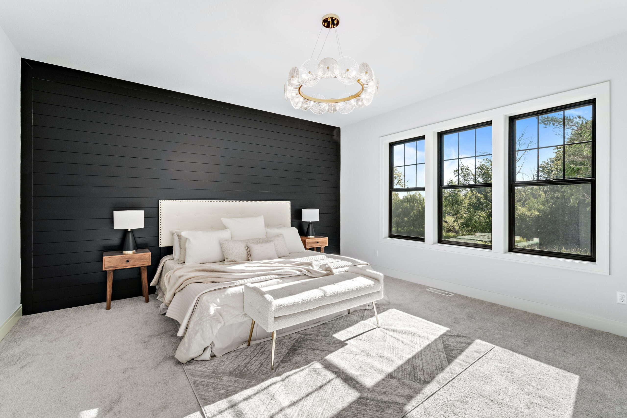 Primary bedroom with black accent wall, large windows, and modern lighting