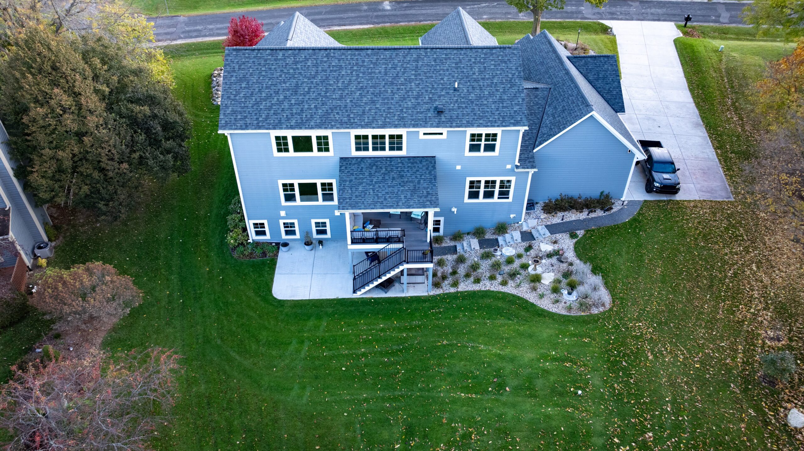 aerial view of custom home backyard with deck, patio, and landscaped yard