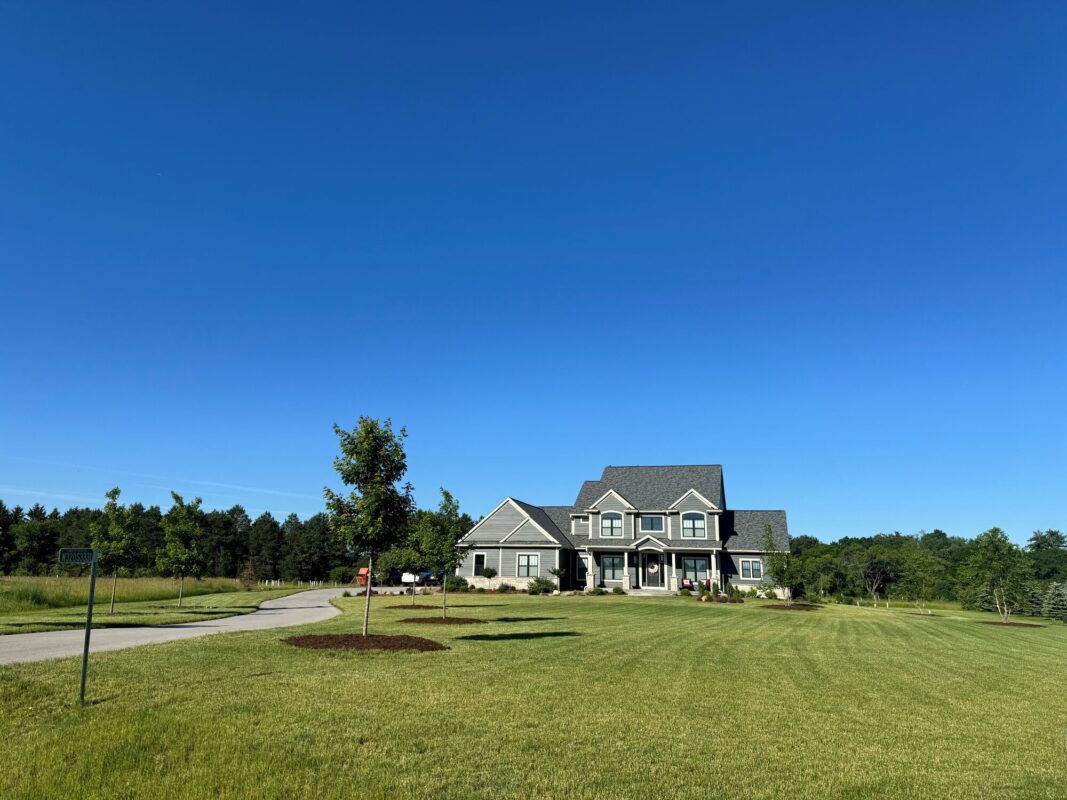 custom home exterior on large lot with wide green lawn and long driveway