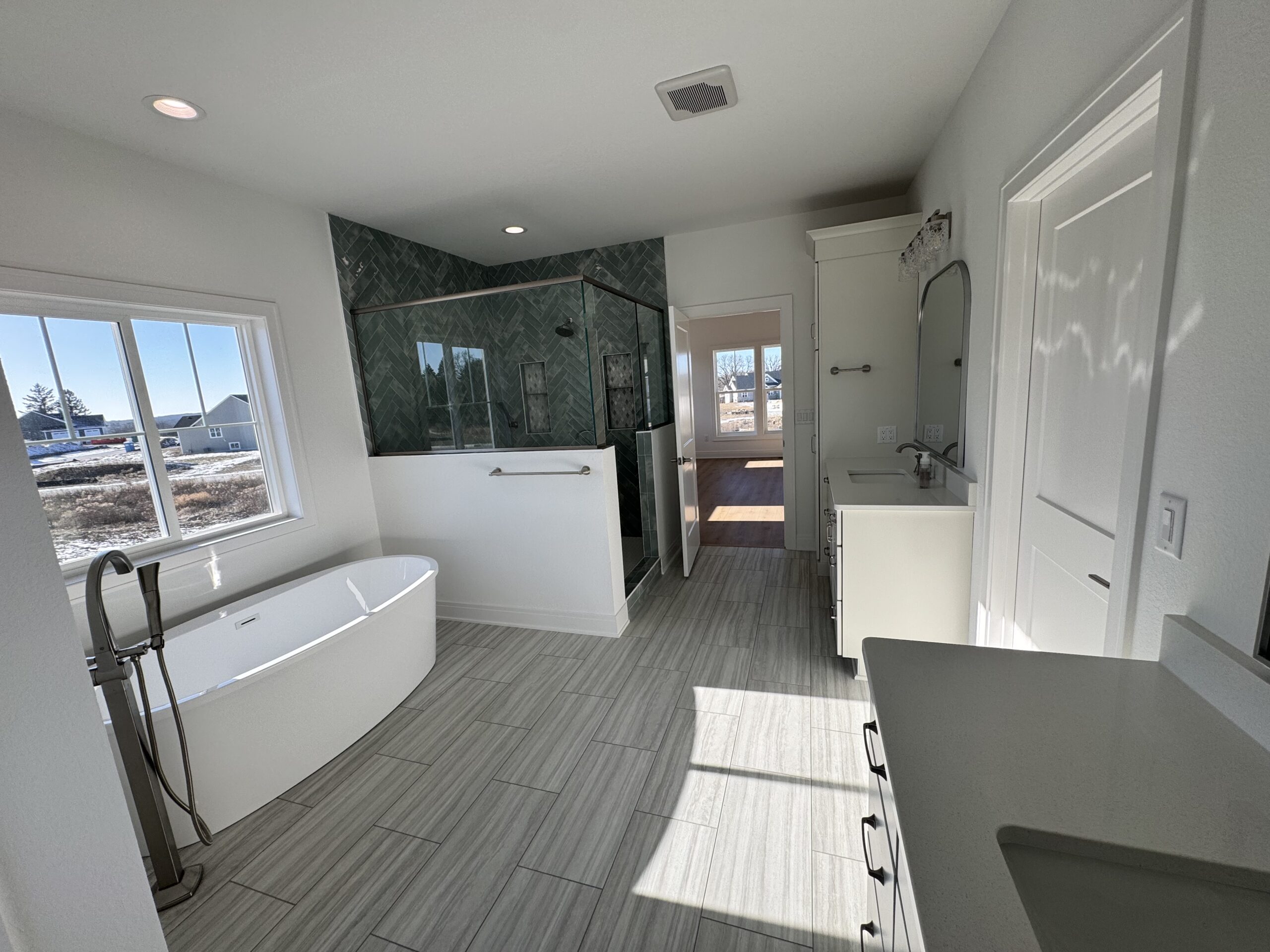 Morrow Home bathroom with freestanding soaking tub, walk-in tile shower, and large window