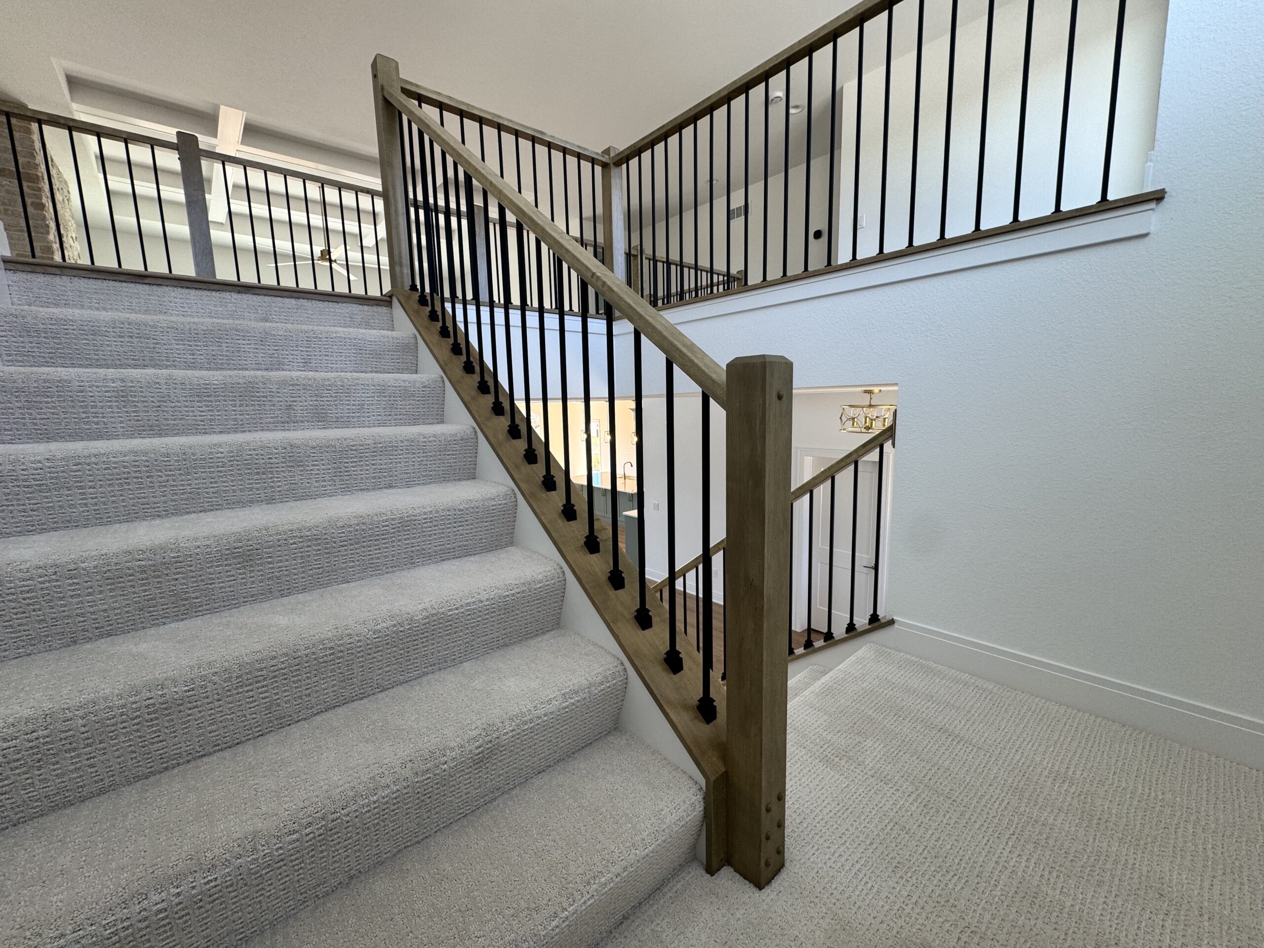 Morrow Home staircase with carpeted steps, wood handrail, and black metal balusters