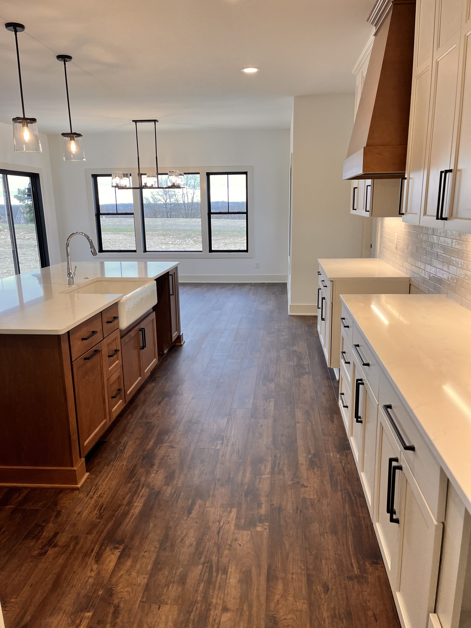 Yaun Home kitchen with white cabinetry, quartz countertops, wood island, and custom range hood