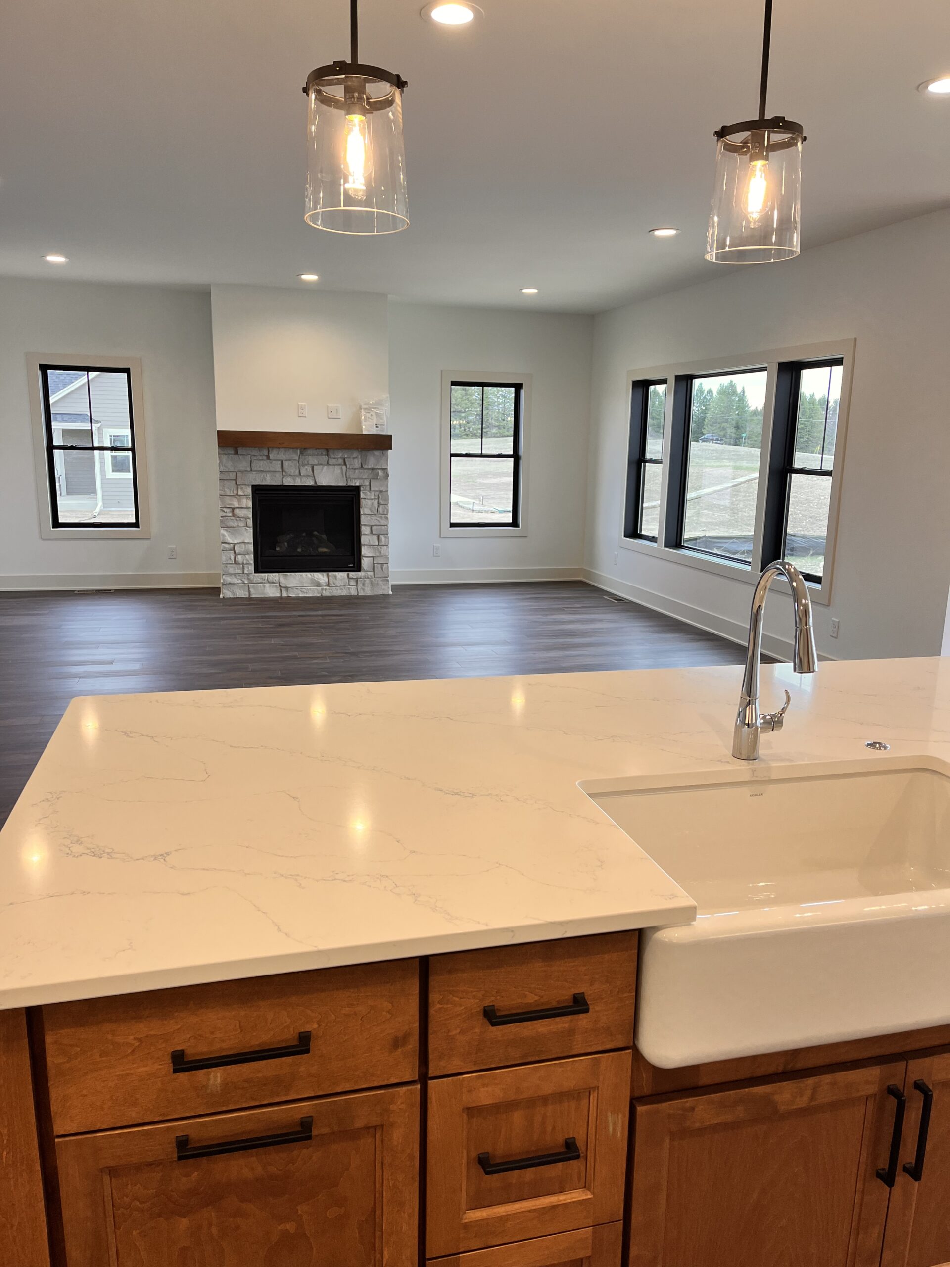 Yaun Home kitchen island with farmhouse sink, quartz countertop, and view into living room with fireplace