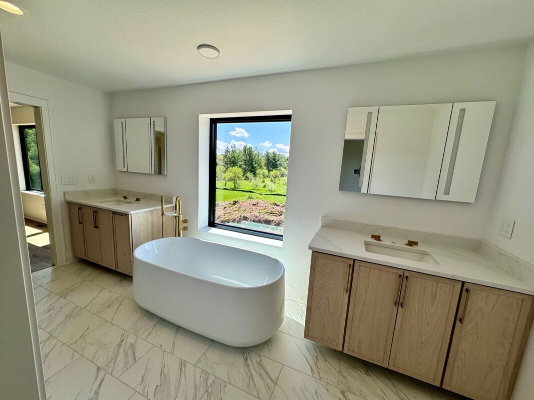 custom home primary bathroom with freestanding tub, double vanity, and large window