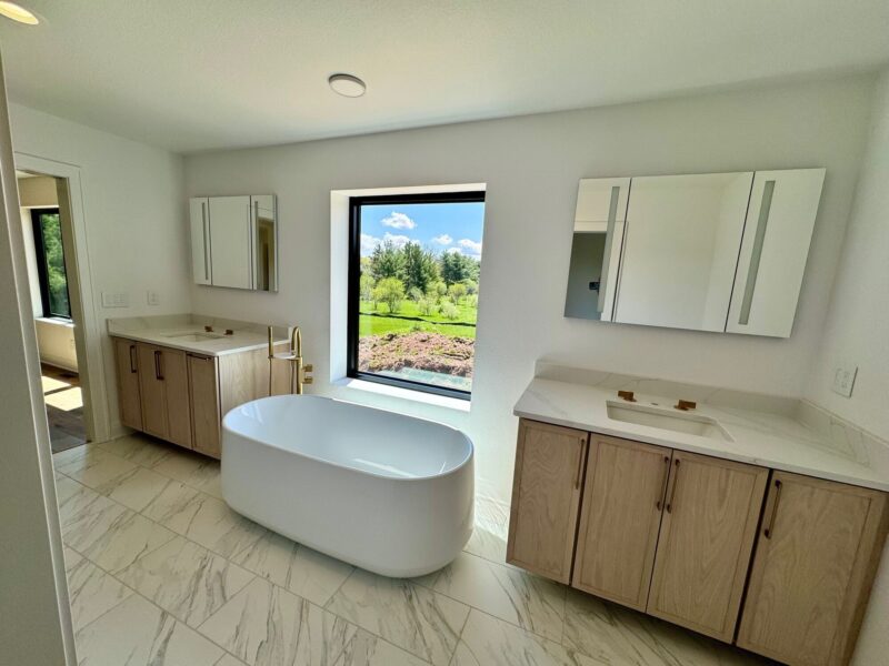 custom home primary bathroom with freestanding tub, double vanity, and large window