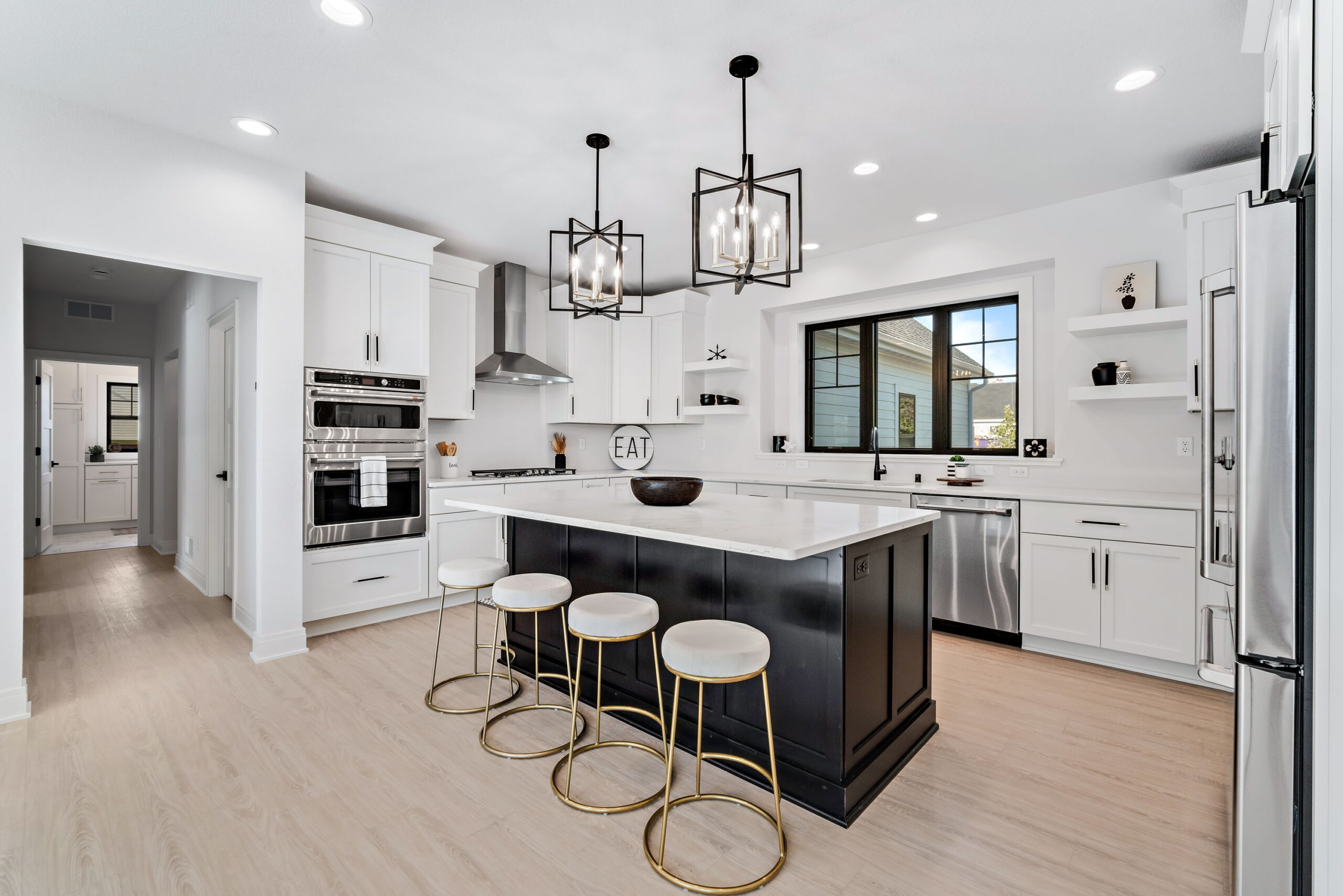 Bright modern kitchen with large island, white cabinetry, stainless steel appliances, and pendant lighting