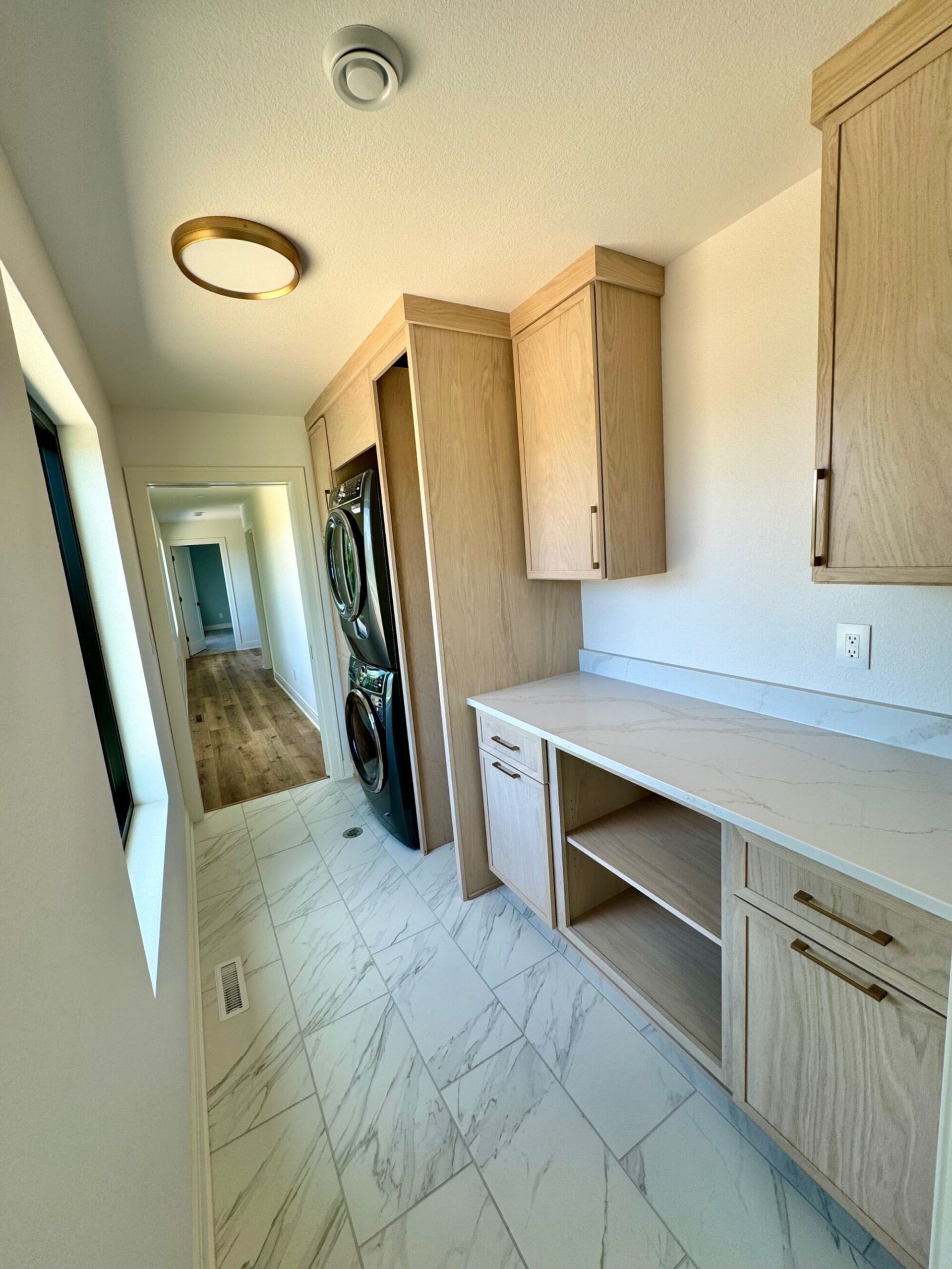 custom home laundry room with built-in cabinets, countertop workspace, and stacked washer and dryer